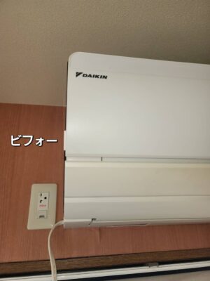 木目調の壁に設置された交換前のダイキン製エアコンと左側のコンセント